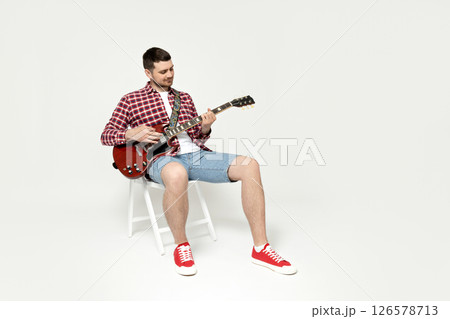 Attractive young guy playing the guitar on a white background 126578713