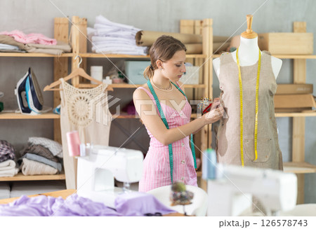 Woman seamstress adjusts clothes on mannequin 126578743