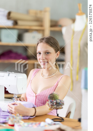 Young seamstress sews a dress on a machine 126578874