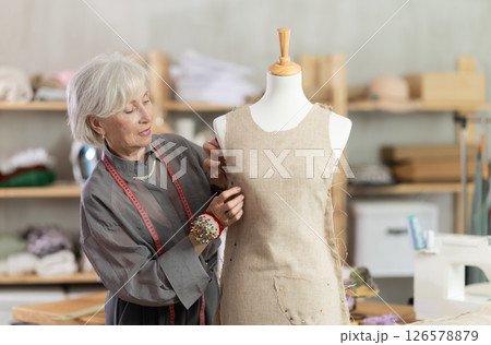 Woman seamstress adjusts clothes on mannequin Woman seamstress adjusts clothes on mannequin 126578879