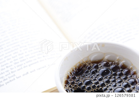 ページを開いた本(洋書)とコーヒーの入ったコーヒーカップで、コーヒーを飲みながら読書を楽しむイメージ ページを開いた本(洋書)とコーヒーの入ったコーヒーカップで、コーヒーを飲みながら読書を楽しむイメージ 126579381