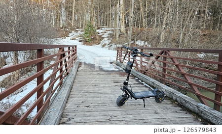 Electric Scooter on Bridge in Winter Landscape, Outdoor Adventure and Eco-Friendly Transportation Electric Scooter on Bridge in Winter Landscape, Outdoor Adventure and Eco-Friendly Transportation 126579843