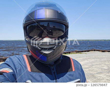 Motorcycle Rider Selfie by the Lake on a Sunny Day, Reflective Visor Shows Road Ahead 126579847