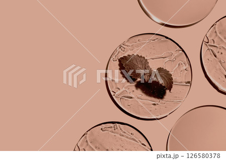 Sample of gels cosmetic product and leaf in petri dish in mocha mousse color 126580378