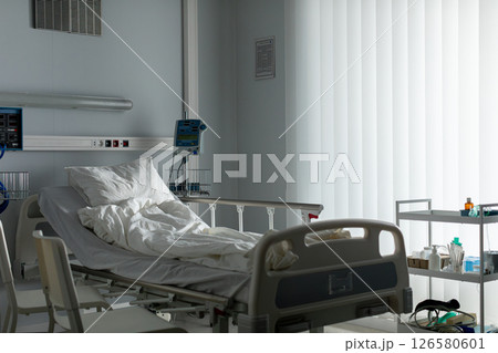 A spacious and empty hospital room featuring a bed along with essential medical equipment A spacious and empty hospital room featuring a bed along with essential medical equipment 126580601