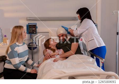 A devoted family supporting their beloved member in a hospital room during recovery and healing A devoted family supporting their beloved member in a hospital room during recovery and healing 126580691