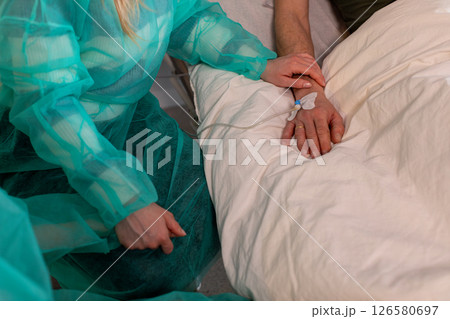 A dedicated healthcare professional is actively assisting a patient comfortably in their bed 126580697