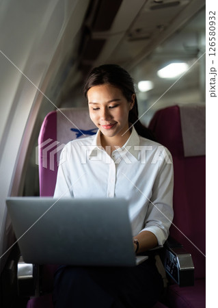 Business Travel. Smiling woman working on a laptop during her flight. Business Travel. Smiling woman working on a laptop during her flight. 126580932