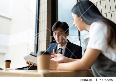 Business Collaboration. Colleagues discussing project plans over coffee in a modern cafe. 126580960
