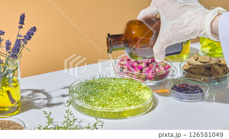 Scientist stirring green herbal infusion during natural cosmetic formulation using essential oils and dried flowers. Oil of tea tree is many use Scientist stirring green herbal infusion during natural cosmetic formulation using essential oils and dried flowers. Oil of tea tree is many use 126581049