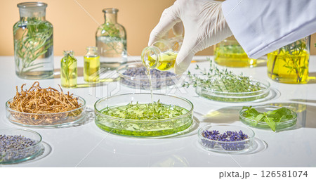 Pouring green herbal liquid into clear glass dishes for testing and examination in a controlled lab environment. Pharmaceutical research warning with herbal green pharmaceuticals 126581074