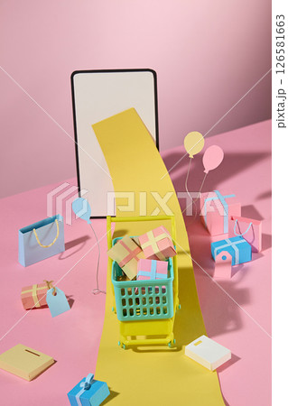 A long yellow receipt flows from the phone screen into the shopping cart, surrounded by colorful boxes, creatively displaying digital transactions. Colorful handmade props decorate the pink background A long yellow receipt flows from the phone screen into the shopping cart, surrounded by colorful boxes, creatively displaying digital transactions. Colorful handmade props decorate the pink background 126581663