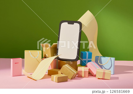 A smart phone sits among cardboard boxes and gift bags, depicting a warehouse-style shipping scene on a green and pink background. Online shopping theme, space for text A smart phone sits among cardboard boxes and gift bags, depicting a warehouse-style shipping scene on a green and pink background. Online shopping theme, space for text 126581669