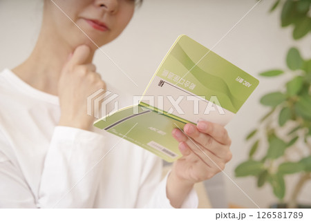 通帳を見て複雑な表情をする女性 通帳を見て複雑な表情をする女性 126581789