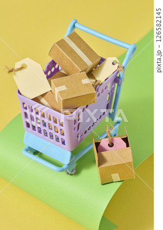A cart overloaded with parcels and paper bags placed on soft pastel curves, visually representing a busy shopping day in a cute paper-crafted form. Paper handmade props, photo for advertising 126582145