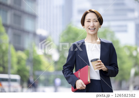 ビジネス　コーヒーカップを持ってオフィス街を歩く女性 126582382