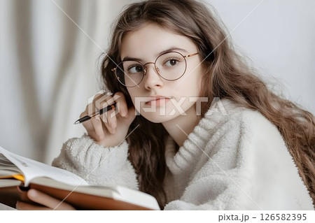 Pensive Young Woman with Round Glasses Studying Pensive Young Woman with Round Glasses Studying 126582395