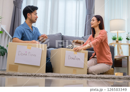 group of friend sorting and packing clothes into a donation box.community support, and charitable giving group of friend sorting and packing clothes into a donation box.community support, and charitable giving 126583349