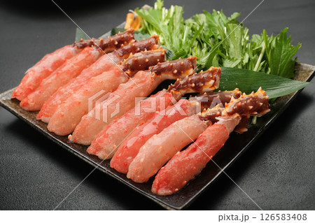 タラバガニのかにしゃぶ（生ポーション）を黒い皿に並べている。背景は黒 126583408