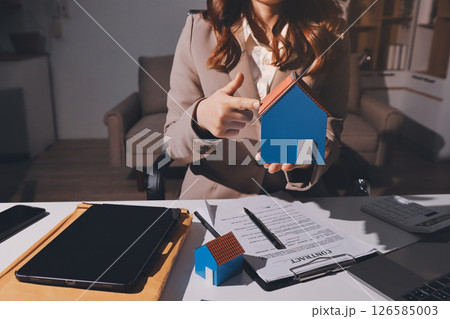 Female Real Estate Broker presenting and advised to model home and building project detail in the office, sign purchase sales contract, agreements concerned mortgage loan offer and insurance. 126585003