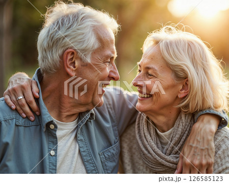 Happy elderly couple embracing and smiling warmly at each other outdoors in a park setting 126585123