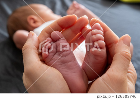 Tender Moment: Adult Hands Holding Newborn Baby Feet Tender Moment: Adult Hands Holding Newborn Baby Feet 126585746