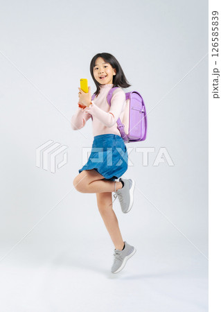 スマホを使いながらジャンプするランドセルを背負った小学生の女の子の全身写真 スマホを使いながらジャンプするランドセルを背負った小学生の女の子の全身写真 126585839