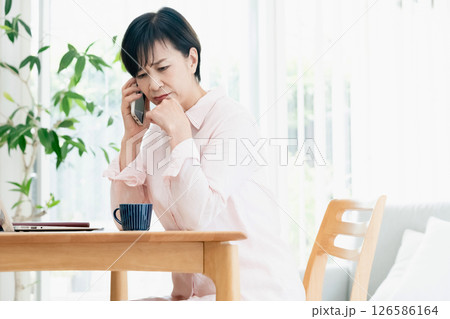 リビングでスマホ通話する中高年女性 リビングでスマホ通話する中高年女性 126586164