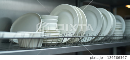 various white ceramic plates on metal shelves 126586567