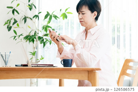 リビングでスマホを操作する中高年女性 リビングでスマホを操作する中高年女性 126586575