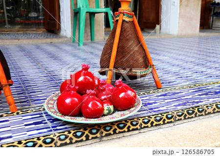 Traditional souvenirs - ceramic garnets of red color, outdoor street market, Iran. The classic Iranian mementos red ceramic pomegranates on colourful clay tiles Traditional souvenirs - ceramic garnets of red color, outdoor street market, Iran. The classic Iranian mementos red ceramic pomegranates on colourful clay tiles 126586705
