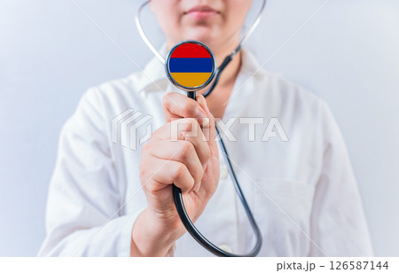 Female doctor holding stethoscope with Armenia flag. National health system of Armenia Female doctor holding stethoscope with Armenia flag. National health system of Armenia 126587144
