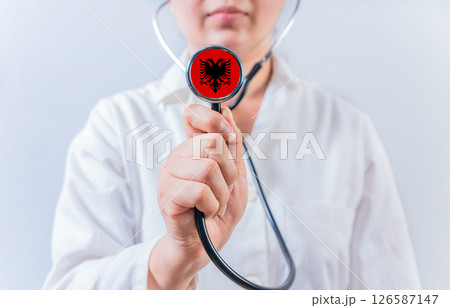 Female doctor holding stethoscope with Albania flag. National health system of Albania 126587147