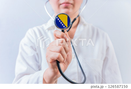 Female doctor holding stethoscope with Bosnia flag. National health system of Bosnia Female doctor holding stethoscope with Bosnia flag. National health system of Bosnia 126587150
