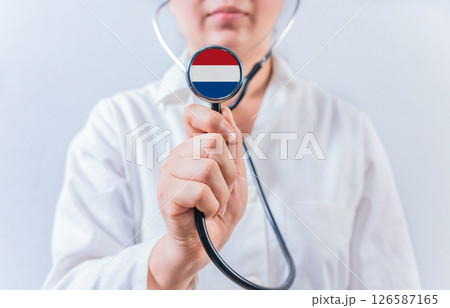 Female doctor holding stethoscope with Dutch flag. National health system of Netherlands 126587165