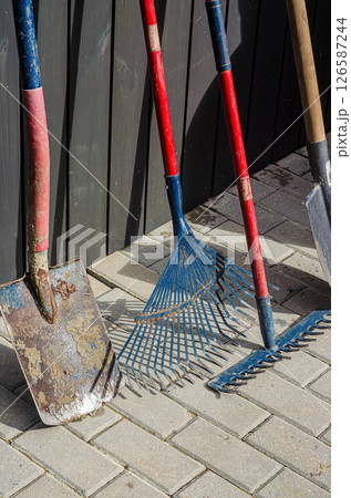 Gardening Tools Leaning on Wooden Fence in Sunlight. High quality photo Gardening Tools Leaning on Wooden Fence in Sunlight. High quality photo 126587244
