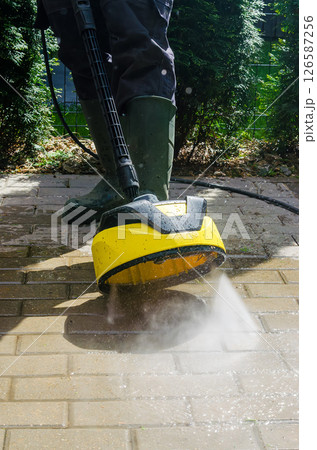 Cleaning dirt with rotating pressure washer head on patio tiles outside. High quality photo Cleaning dirt with rotating pressure washer head on patio tiles outside. High quality photo 126587256
