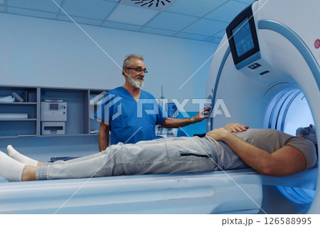 Male patient undergoing CT scan examination in hospital. 126588995