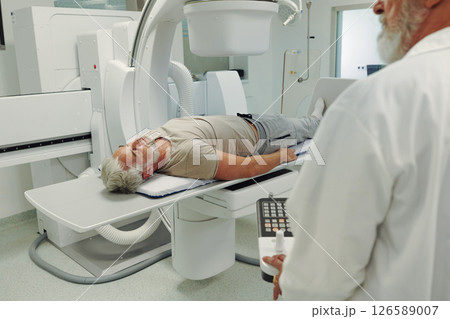 Male patient undergoing CT scan examination in hospital. 126589007