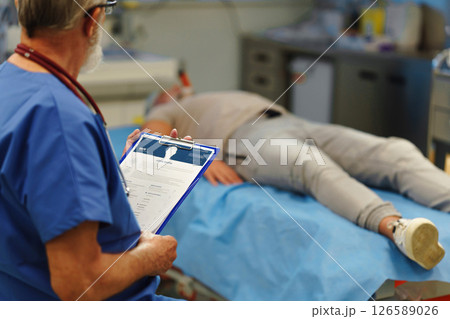 Medical professional examining health record patient lying on examination table 126589026
