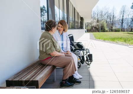 Elderly patient talking with caring female physician in front of hospital. 126589037
