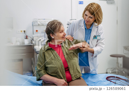 Geriatrician examining senior woman's mobility during routine check-up, Geriatrician examining senior woman's mobility during routine check-up, 126589061