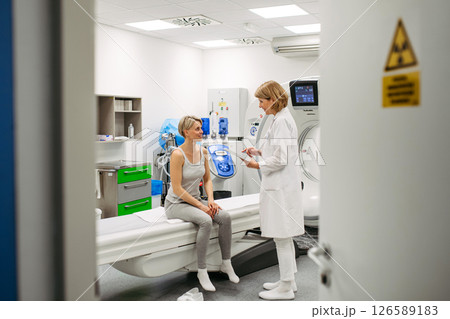 Doctor sharing positive CT scan results with smiling patient in imaging room 126589183