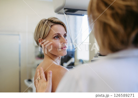Medical professional calming patient ahead of mammogram procedure. 126589271