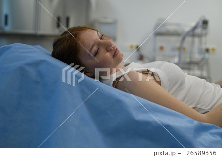 Teenage girl waiting for medical examination, lying on hospital bed. 126589356