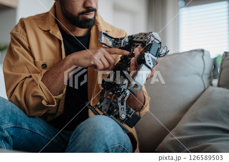 Handsome engineer student working on robot project at home. Handsome engineer student working on robot project at home. 126589503