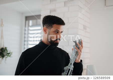 Portrait of young engineer holding robotic arm. Portrait of young engineer holding robotic arm. 126589509