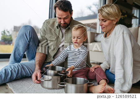 Parents and toddler son playing drums on kitchen pots Parents and toddler son playing drums on kitchen pots 126589521