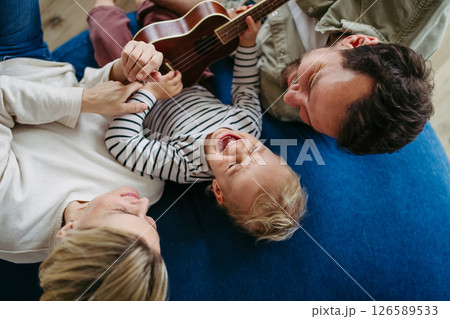 Family bonding moment. Little boy playing on guitar for his family. 126589533