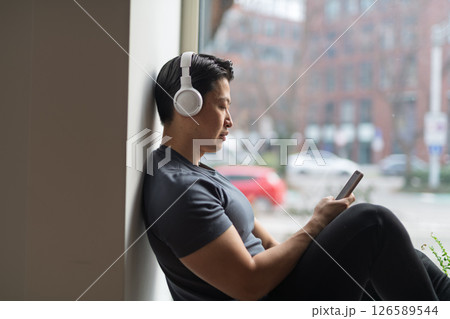 Hygge moment for young man sitting by window and listening music. 126589544
